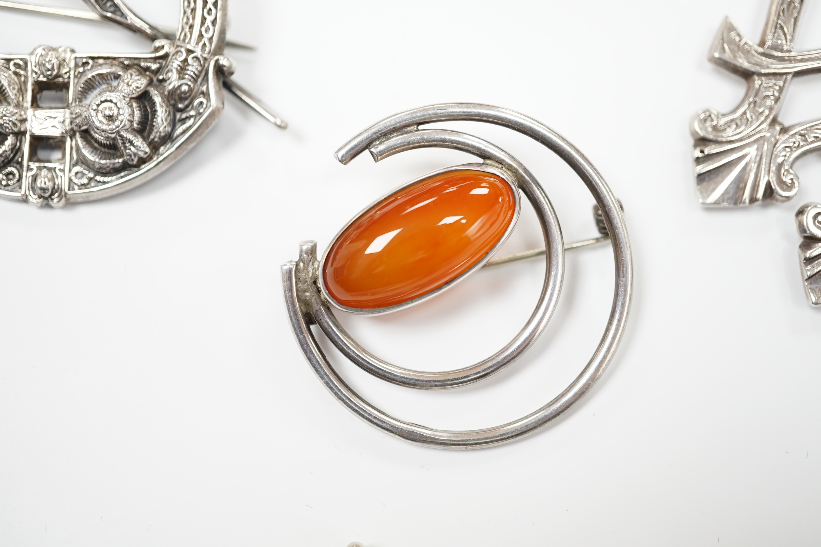 A 1950's Scottish silver and citrine coloured paste set circular brooch, 68mm, an Edwardian silver Celtic style brooch and three other white metal brooches, including Scottish hardstone set.